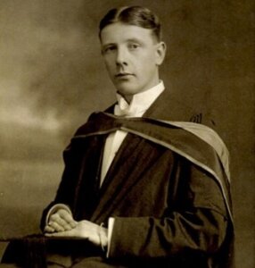A black and white photo of Dr James Walker Wood in graduation robes. a.
