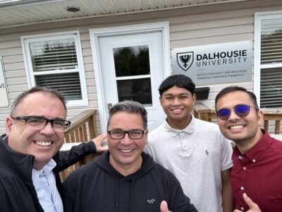 A group of men posing together in front of a building with a Dalhousie University sign