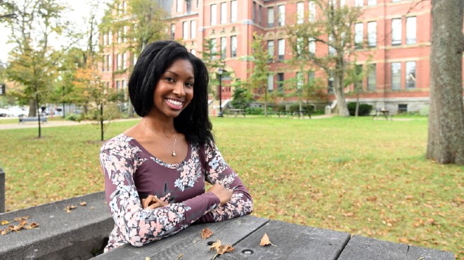 Keisha Jefferies smiles sitting outside at a picnic table on Dalhousie campus in the fall.
